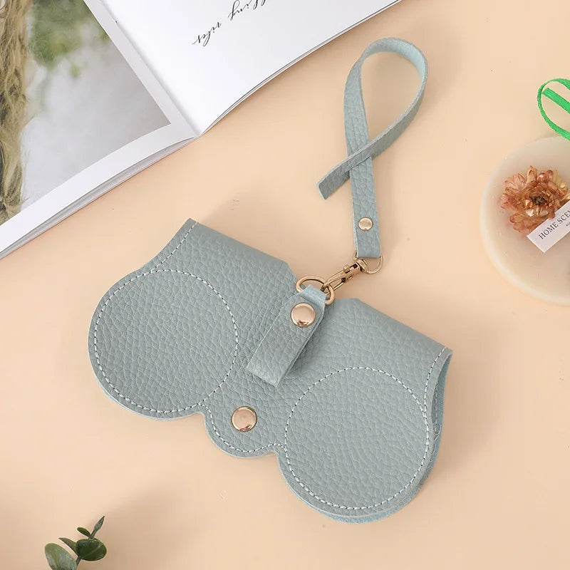 A light gray, padded pouch with a strap is shown next to an open notebook.