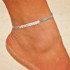 Silbernes geometrisches Knöchelarmband, getragen am Knöchel einer Frau auf hellem Hautton.
