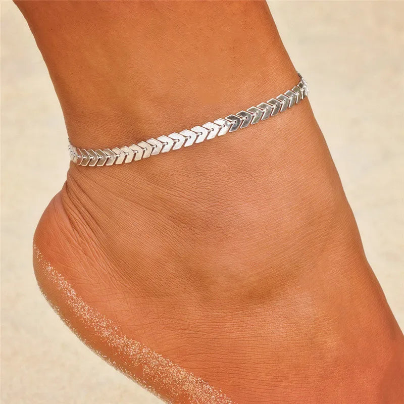 Silver geometric anklet bracelet worn on a woman's ankle.