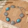 Silver and turquoise beaded necklace bracelet set displayed on a light brown textured surface