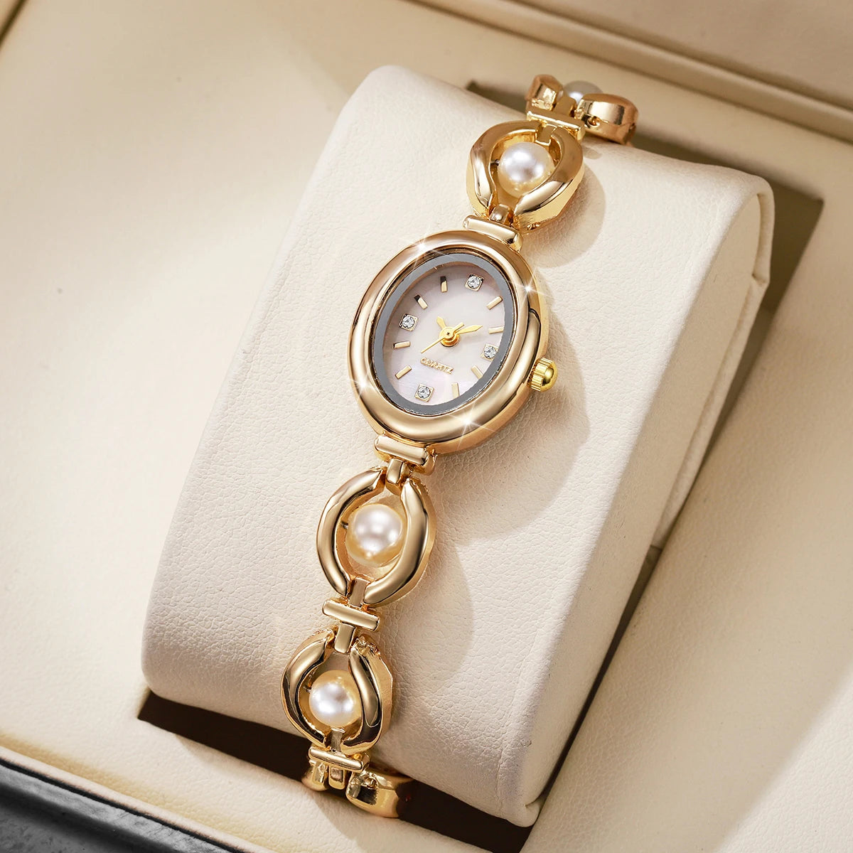 Elegentliche Perlmutt-Quarz-Armbanduhr in Goldton auf einer hellbeigen Box.