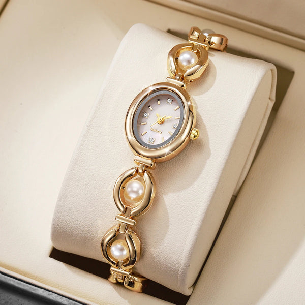 A gold-toned elegant pearl quartz wristwatch resting on a light beige box.