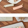 A set of rubber braided ponytail holders and scrunchies in various shades of brown, beige, and pink arranged on a white plate