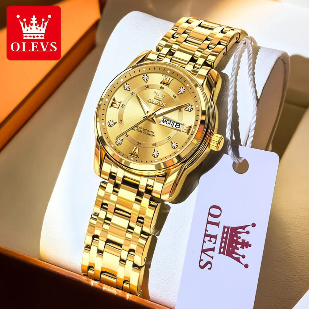 A gold-toned ELEVS watch with a stainless steel bracelet and white strap displayed in a box.