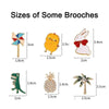 A collection of various sized brooches, including a yellow pin, a white pin, a green pin, and a pineapple-shaped pin.