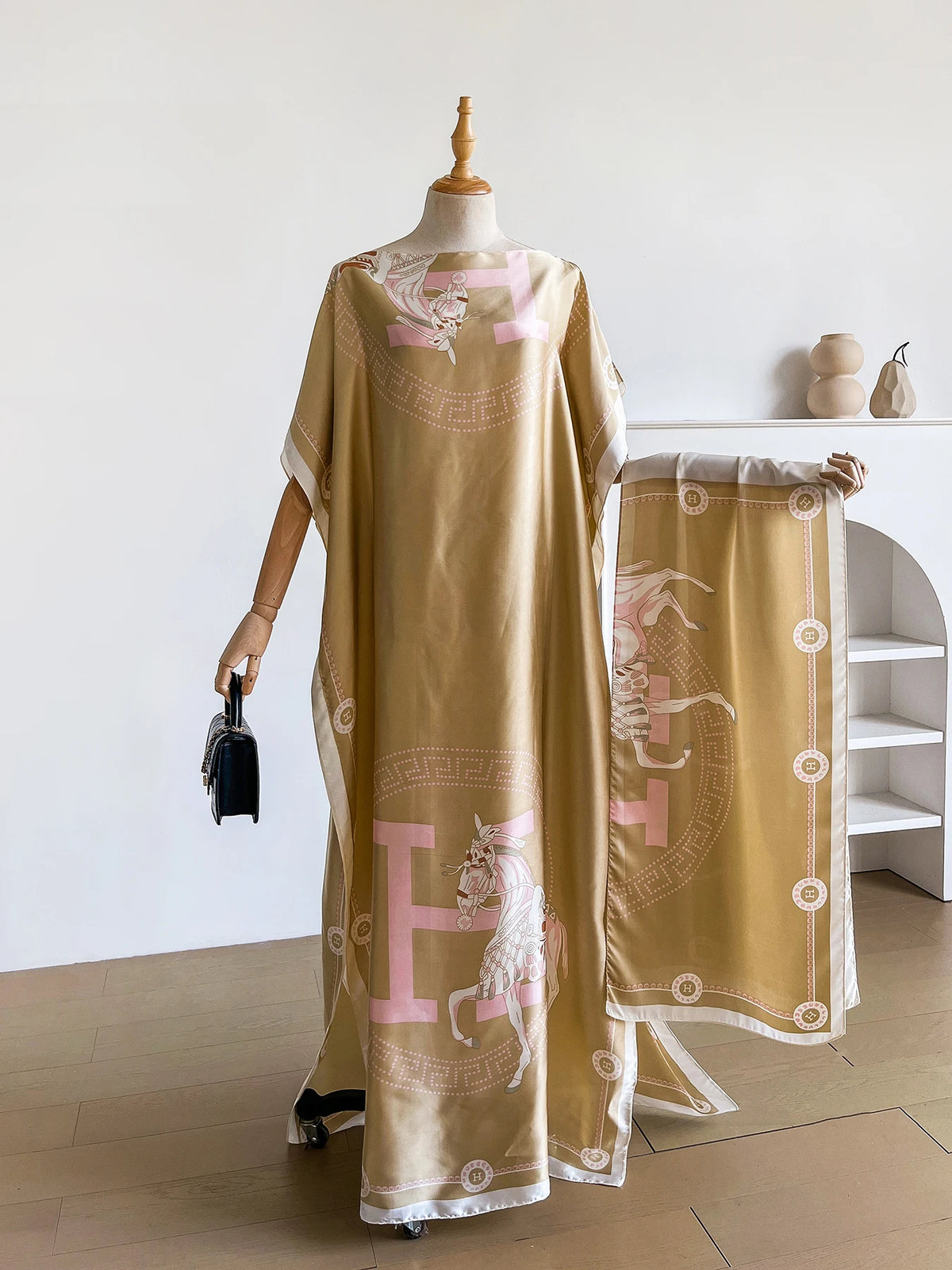 Una caftán abaya beige con un delicado estampado de caballo rosa exhibido en un maniquí.