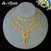A set of luxury gold plated bridal jewelry featuring layered necklaces and a pendant displayed on a gray stand.