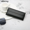 A black elegant leather eyeglass case lying on a white surface next to a white cup and sunglasses.
