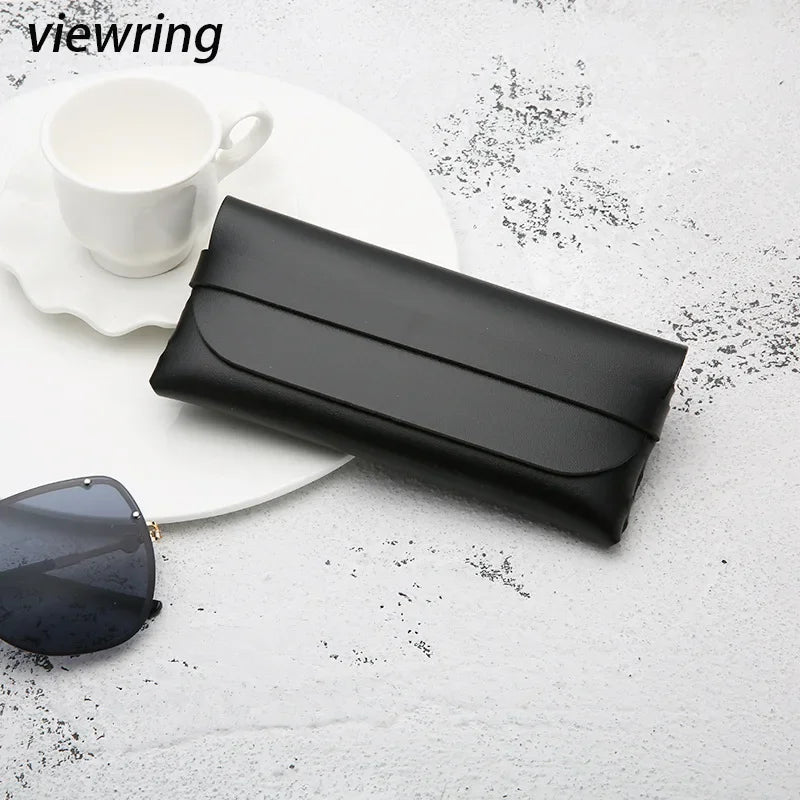 A black elegant leather eyeglass case lying on a white surface next to a white cup and sunglasses.