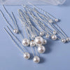 A collection of 18 faux pearl hair pins with silver wires arranged on a light blue surface.