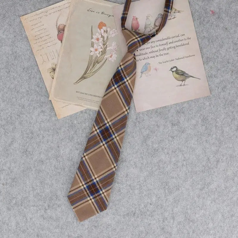 A plaid necktie featuring a brown and tan pattern is displayed alongside vintage-style paper documents.