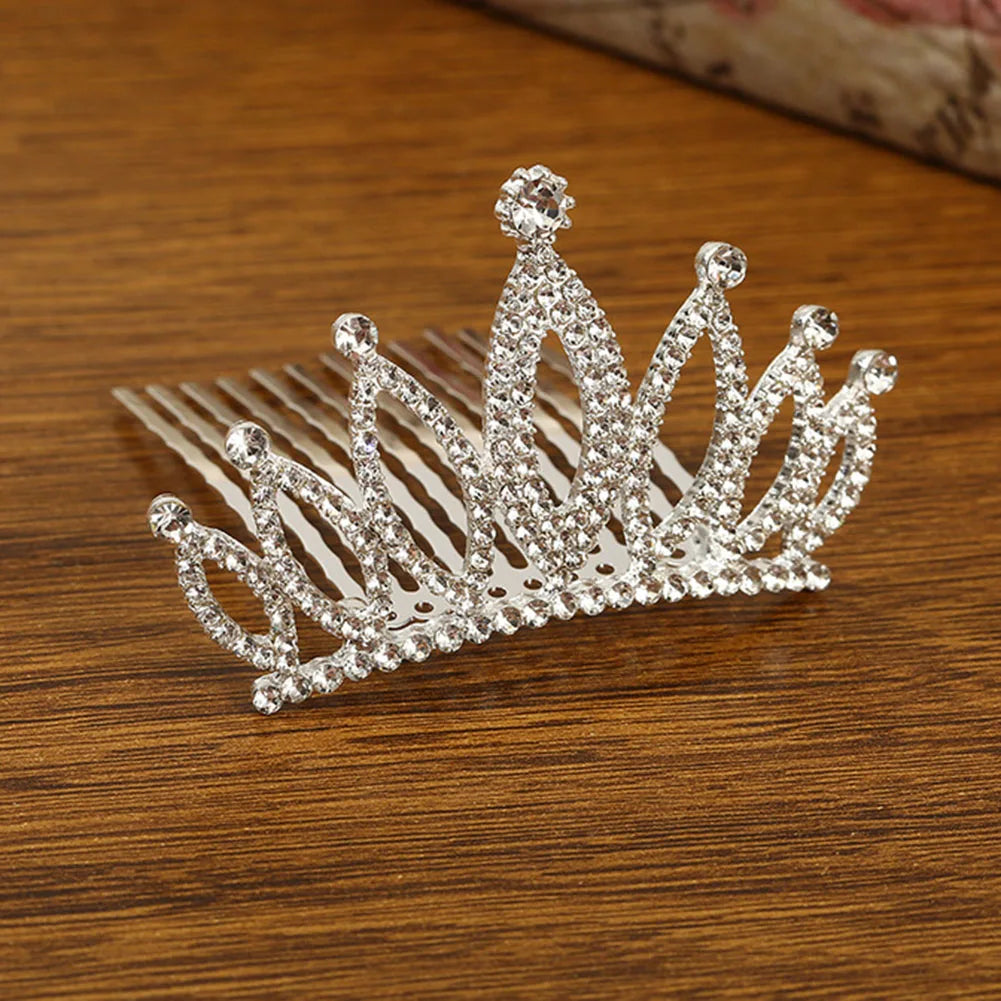 A sparkling crystal princess tiara hair comb for women made of clear rhinestones resting on a wooden surface.