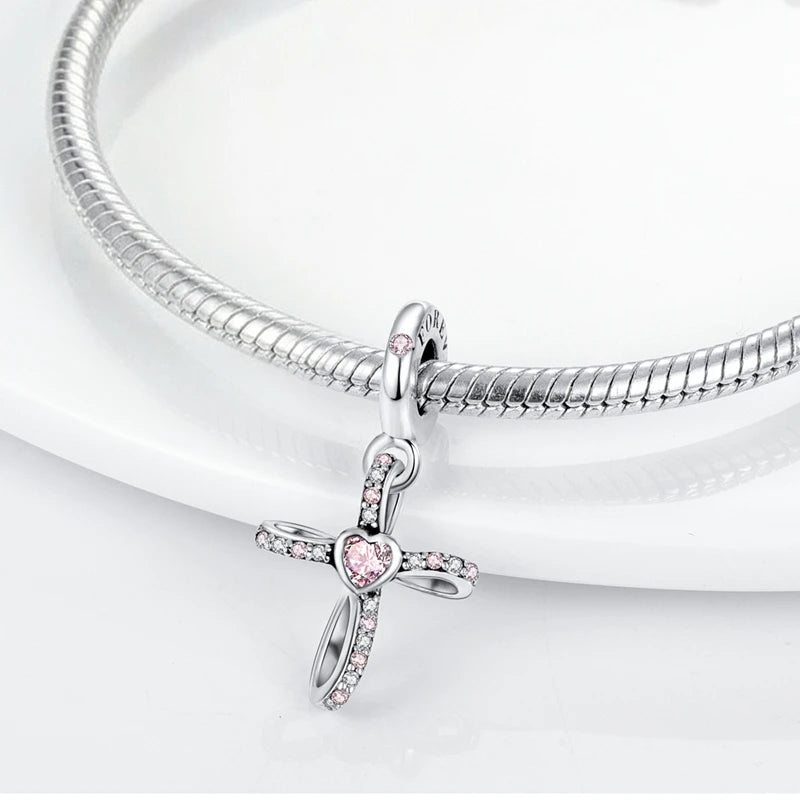 A sterling silver devil's eye charm bracelet with a cross pendant displayed on a white background.