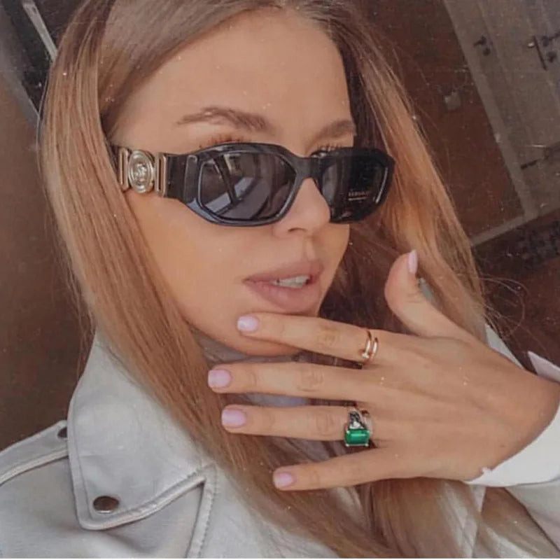 Eine Frau mit Vintage-Designer-Sonnenbrille und leichter Jacke schaut in die Kamera.