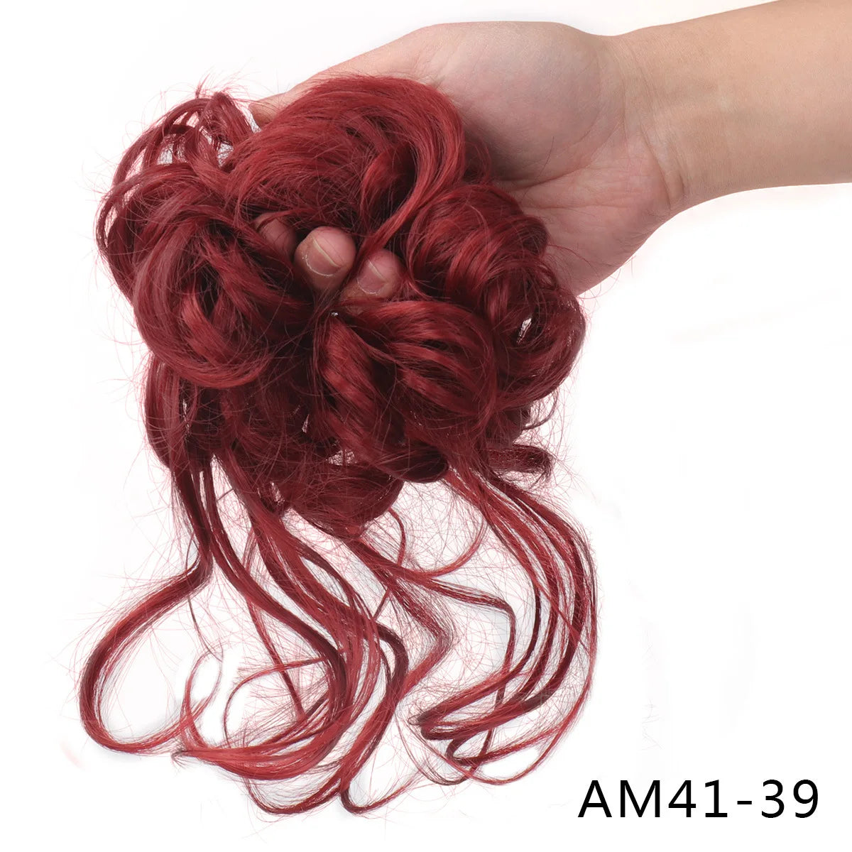 A hand holds a messy red synthetic hairpiece bun for women.