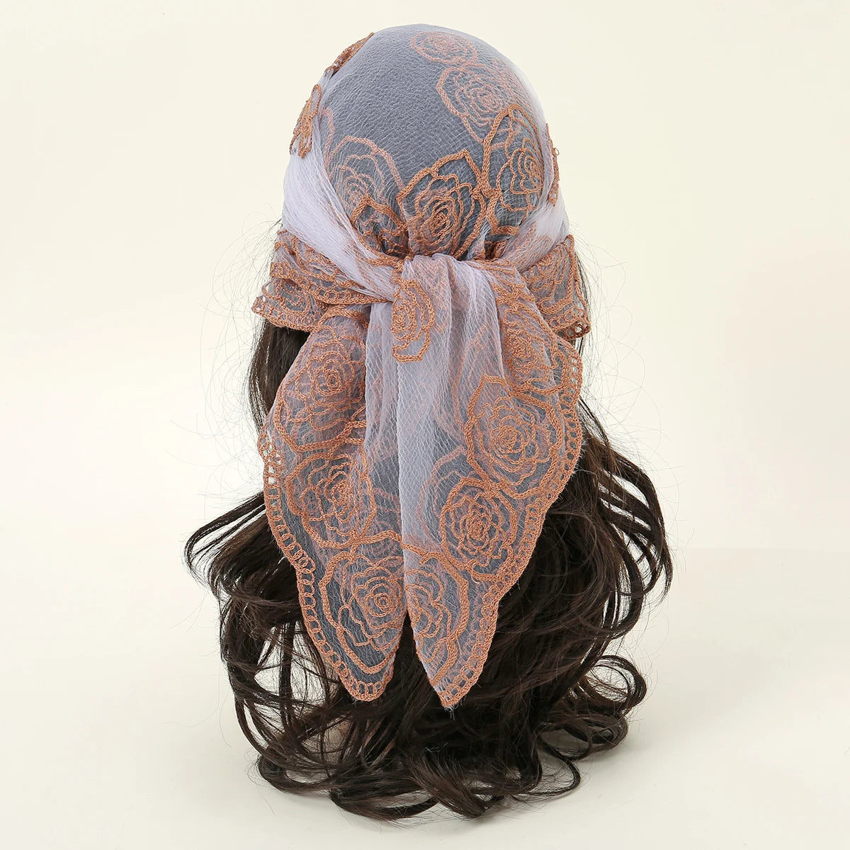 A close-up of a floral embroidered lace bandana headscarf tied around dark hair.