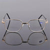 A pair of thin, gold-rimmed bifocal reading glasses resting on a reflective surface.