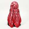 A vibrant red silk scarf with a white leopard print pattern tied around a woman's dark hair.
