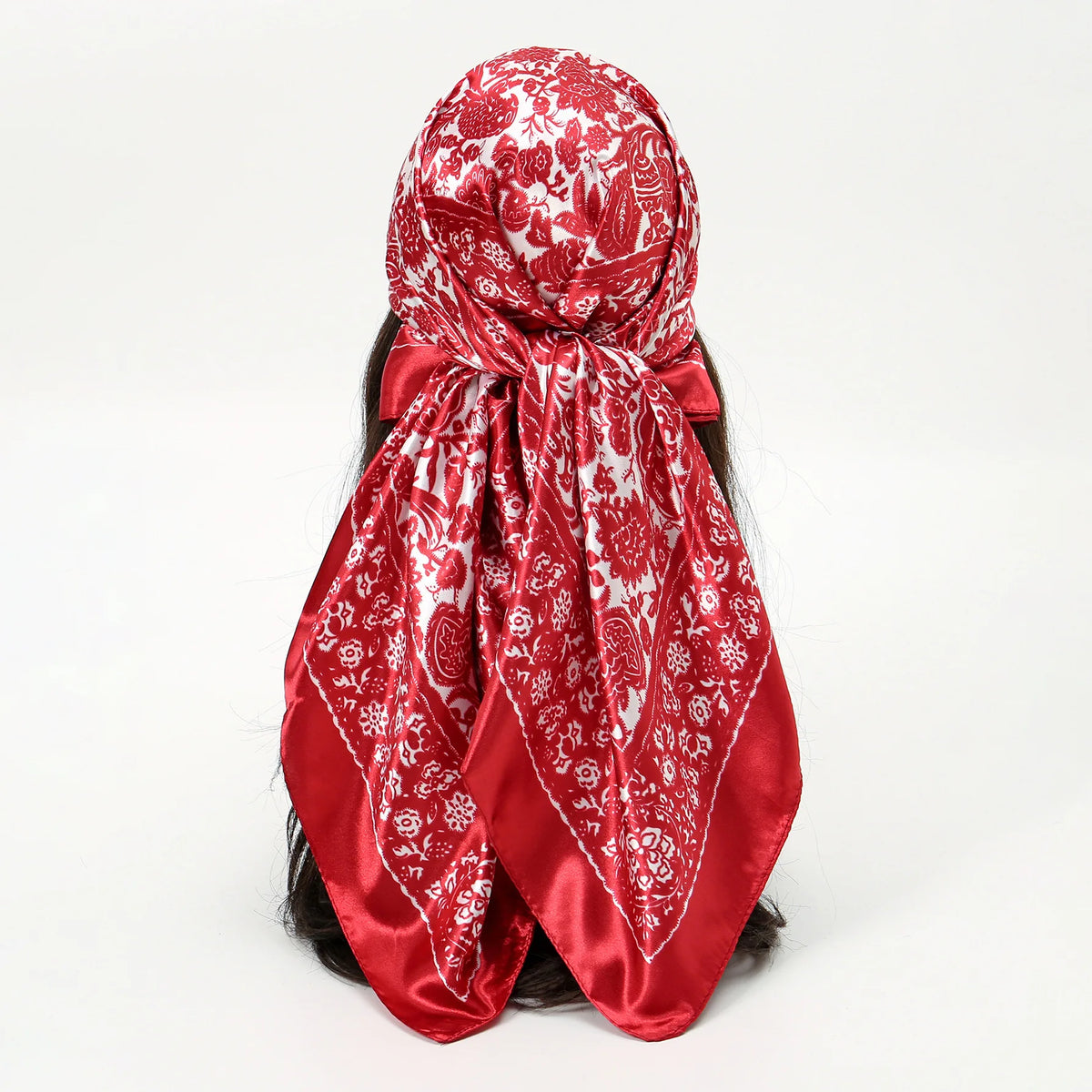 A vibrant red silk scarf with a white leopard print pattern tied around a woman's dark hair.