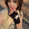 Una mujer vistiendo una blusa amarilla y guantes de punto negros con diseño de estrella blanca.