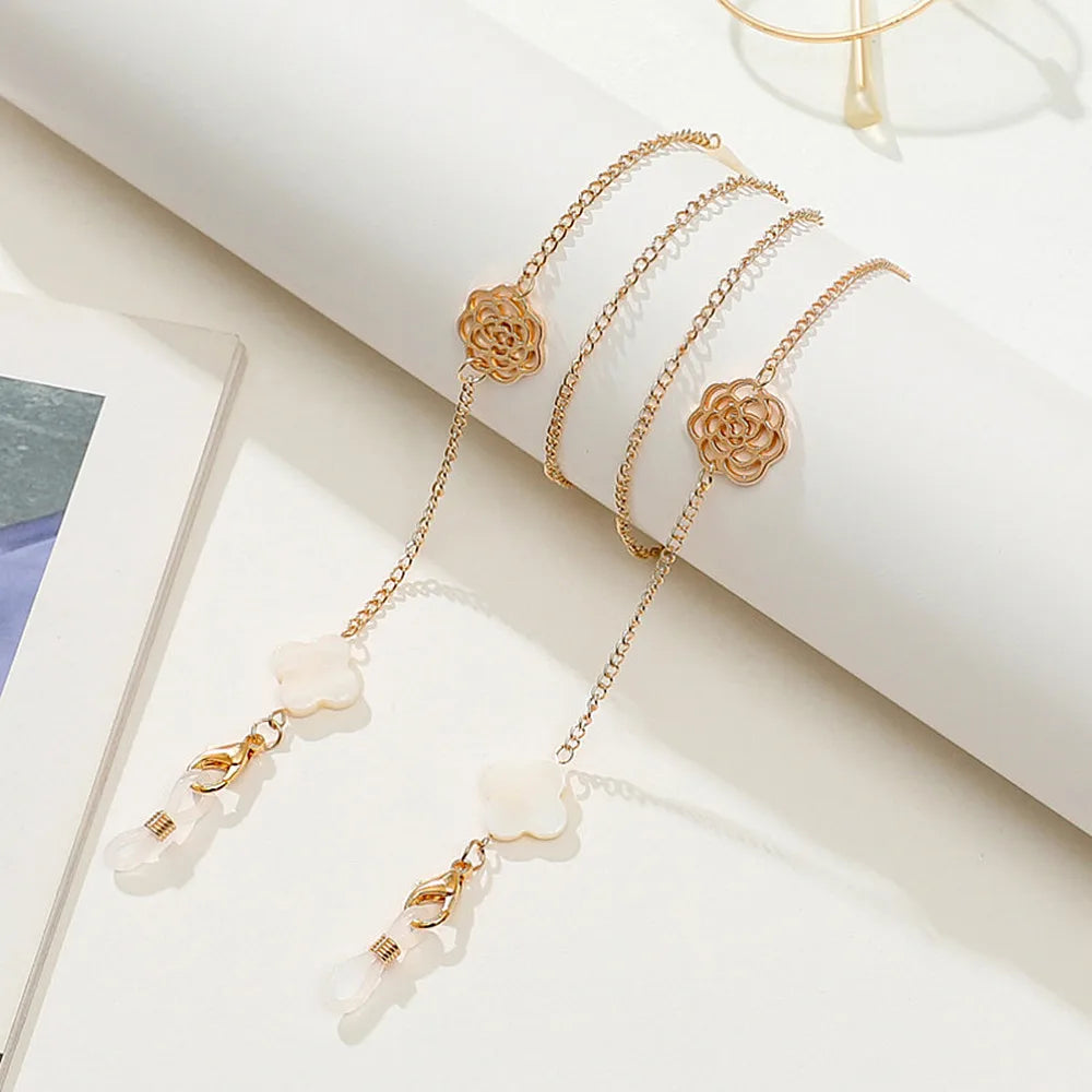 A delicate gold-toned chain necklace featuring rose and pearl charms displayed on a white background.