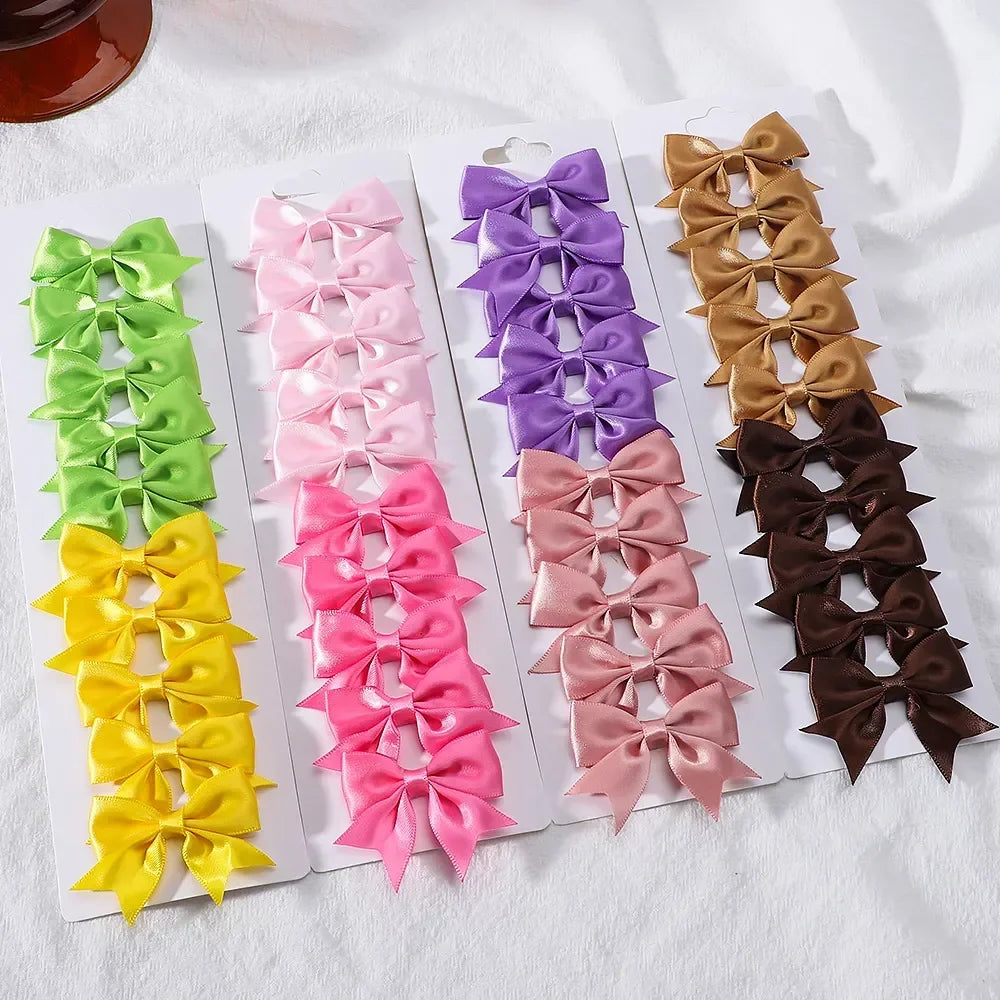 A display of nine handmade ribbon bow hair clips in various shades of green, pink, purple, and brown.