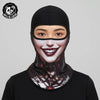 A woman wearing a black full face balaclava helmet liner with a stylized face design.