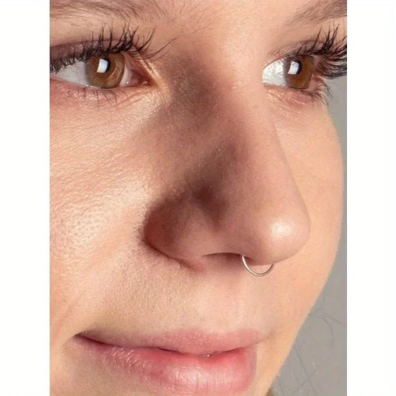 Close-up of a woman's nose showing a small silver hoop septum ring.