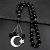 A black beaded necklace with a silver crescent moon and star pendant on a dark background.