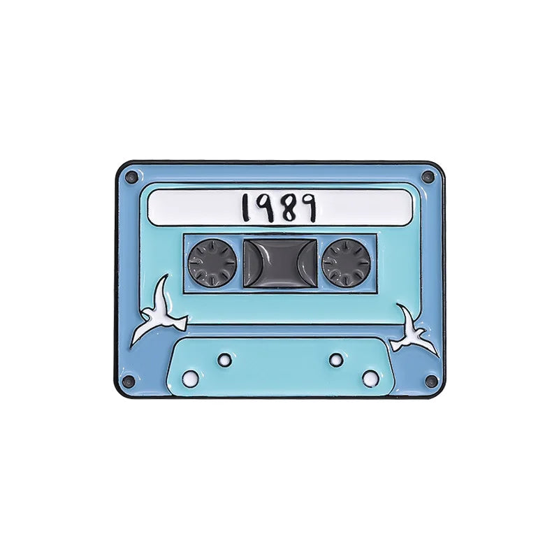 A retro fine line cassette enamel pin brooch featuring a light blue body and the year 1989 on the label.