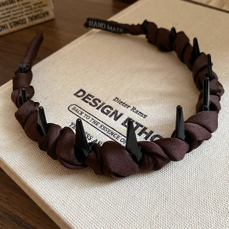 A brown resin wave toothed headband is displayed on a light-colored surface.