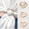 Gold and silver rhinestone and pearl decorative button clips displayed on a white fabric background.