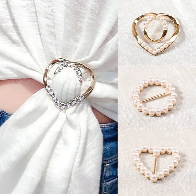 Gold and silver rhinestone and pearl decorative button clips displayed on a white fabric background.