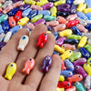 A close-up of a hand holding an assortment of colorful ceramic fish charms for DIY jewelry.