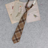 A brown and blue plaid necktie is displayed alongside vintage-style paper documents.