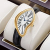 A gold-toned retro quartz watch with an irregular white face and black leather strap is displayed in a light-colored box.