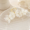 A gold pearl rhinestone butterfly hair claw clip resting on a white ceramic plate.