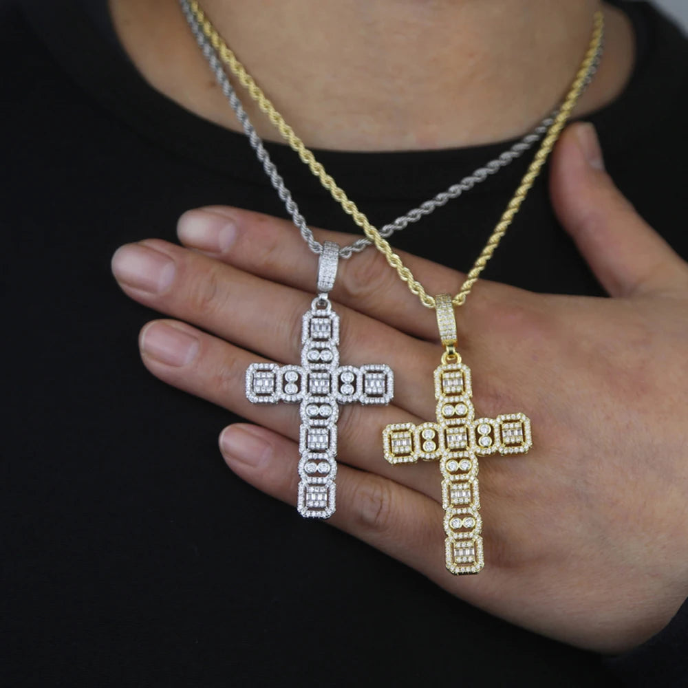 Une main tient un pendentif de croix en or et argent serti contre un t-shirt noir.