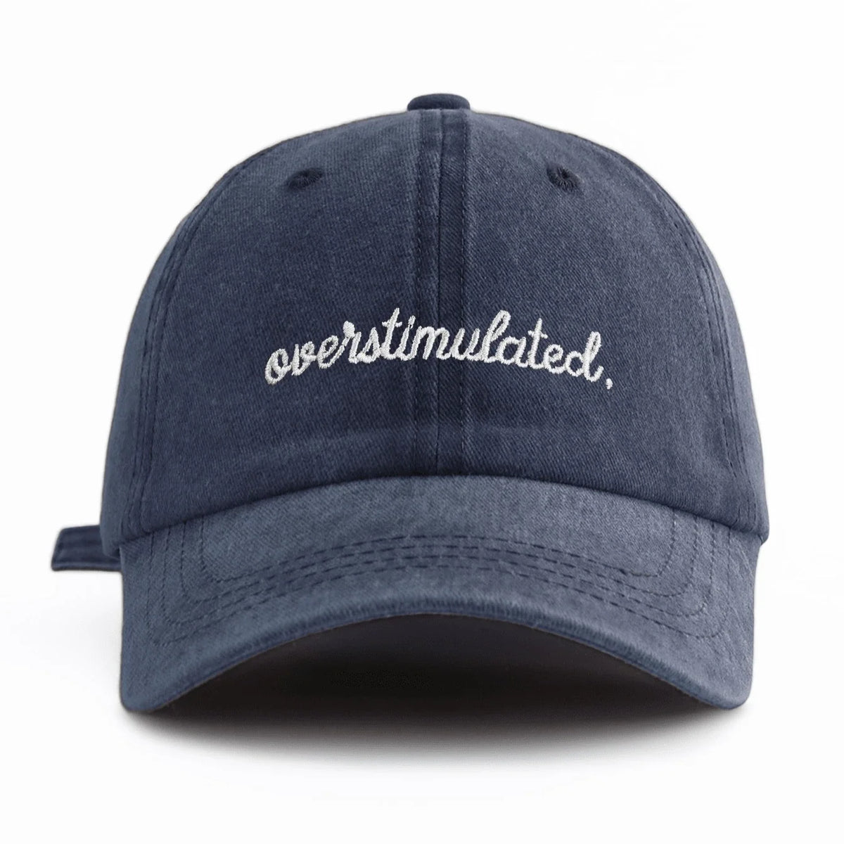 A dark navy blue baseball cap with white embroidered text that reads overstimulated