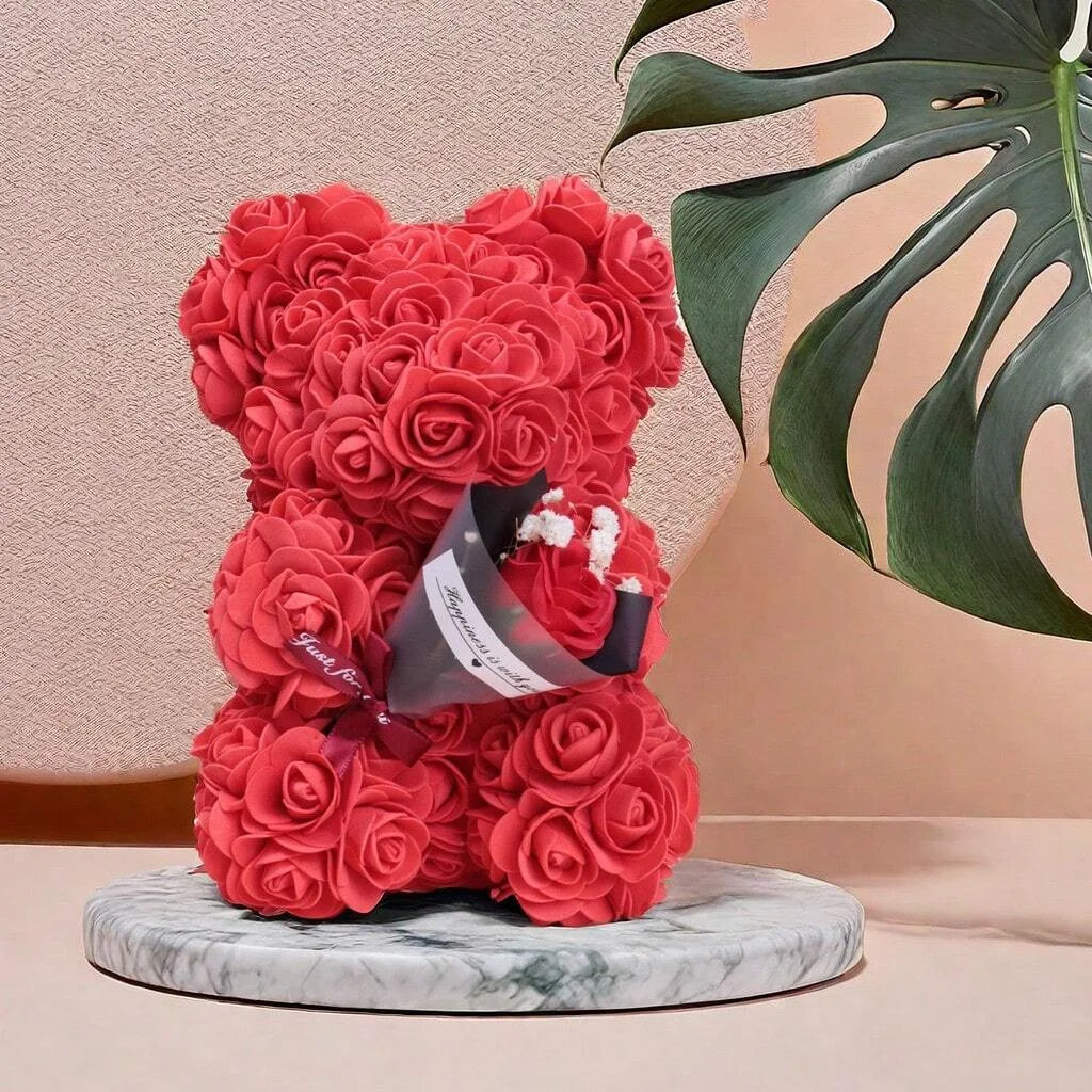 Bouquet de ours en peluche rose à la mousse douce rouge, présenté sur un socle de marbre à côté d'une feuille tropicale verte