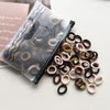 A pile of natural colored elastic hair bands, including brown and beige, next to a clear plastic pouch.