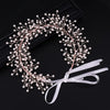 A delicate pink pearl hair vine wreath with a white ribbon bow.