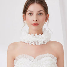 Une femme modélise un pull à col volanté plissé et décoratif blanc.