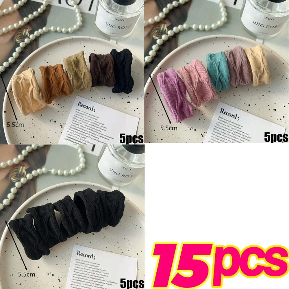 A collection of extra-wide elastic hair bands in various shades of beige, brown, black, and teal displayed on a white plate.