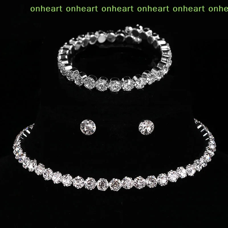 A set of four crystal jewelry pieces including a ring, bracelet, and earrings displayed on a black background.