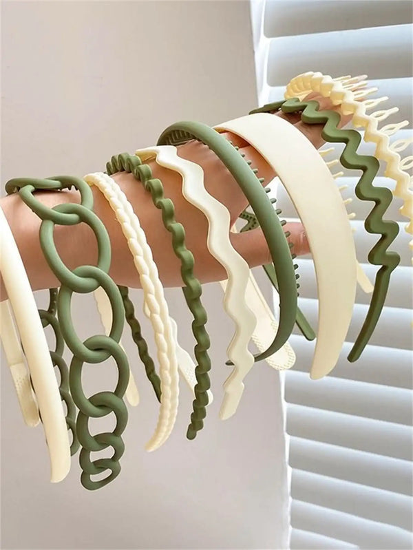 A display of various green and cream hair accessories headbands on a person's hand.