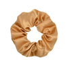 A close-up of a golden satin fabric scrunchie tied in a bow shape.