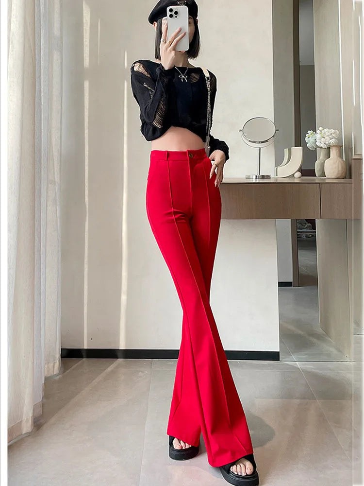A woman models high-waist red flare skinny pants and a black top in a bright indoor setting.