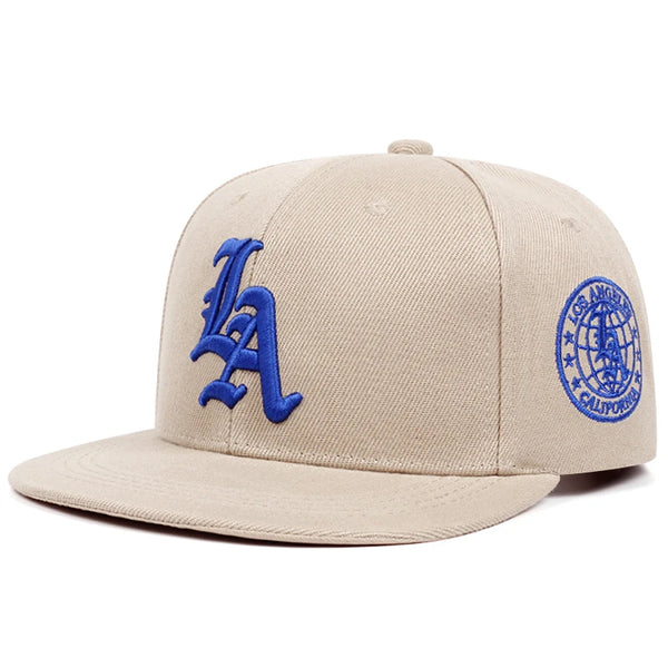 A beige embroidered cotton flat edge baseball cap featuring a blue LA logo and an Los Angeles California emblem.