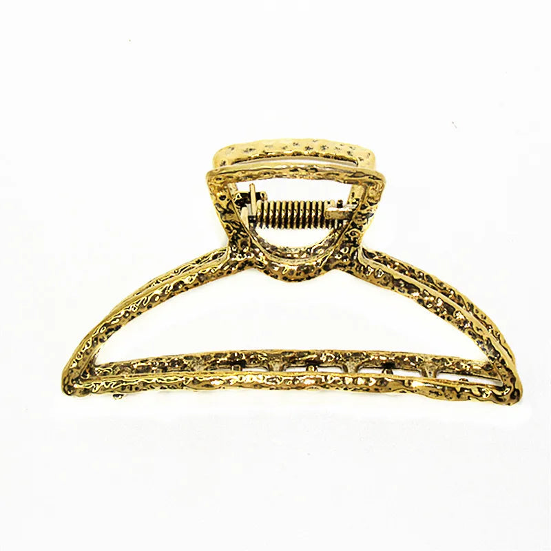 Gold metal hair claw clips with a decorative design and a spring-loaded mechanism.